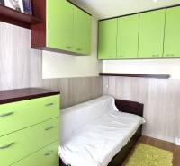 A room in a 3-room apartment with a white sofa, green cabinets, and a wooden decor floor.