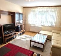 Living room with a beige sofa and dark wood furniture in a three-room apartment.