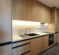 A kitchen with wooden decor, black details, built-in appliances in a 3-room apartment.