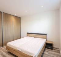 A bedroom in a 3-room apartment with a wood-patterned floor and a large built-in wardrobe.