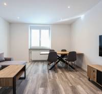 Living room with wood-patterned flooring, a sofa, a dining table, and a television in a 3-room apartment.