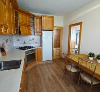 A kitchen in a 3-room apartment with a wooden decor floor and a corner kitchen unit.