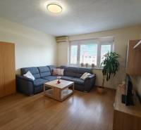 Living room with a corner sofa, wooden decor flooring, and a TV in a 3-room apartment.