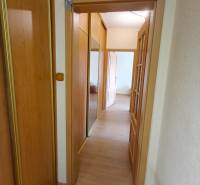 A hallway in a 3-room apartment with a wooden-patterned floor and a mirrored wardrobe.