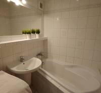 Bathroom with a bathtub and a sink in a 3-room apartment, white tiles and decorations.
