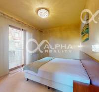 A bedroom in a two-room apartment with curtains and a chandelier, a bed, and nightstands.