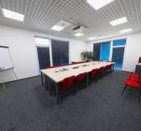 Conference room with a long table, red chairs, and a flipchart in the offices.