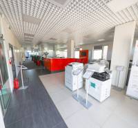 The interior of an office with printers, a red reception desk, and a high ceiling.