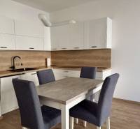 A kitchen in a 2-room apartment with white cabinets and a wooden decor floor.