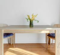 A dining table with a flower vase on the floor with wooden decor in a 2-room apartment.