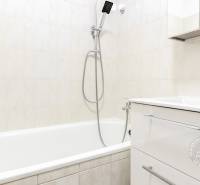 A bathroom with a white bathtub and sink in a two-room apartment.