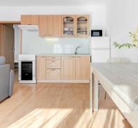 A kitchen in a 2-room apartment with a wood-patterned floor and a dining table.