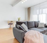 A bright living room with wood-patterned flooring, a comfortable sofa, and a dining area.