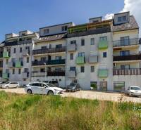 A building with apartments on Vincent Šikula Street in Stupava surrounded by cars and greenery.