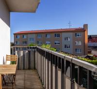 The balcony of a 2-room apartment on Vincent Šikula in Stupava, with outdoor seating and greenery.