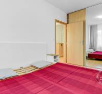 Bedroom in a 2-room apartment with a large mirrored wardrobe and a wooden decor floor.