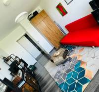 Living room in a 3-room apartment with a red sofa and a wooden decor floor.
