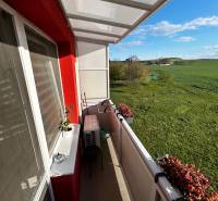 The balcony of a 3-room apartment in Gbeľy with a view of green meadows and flowers.