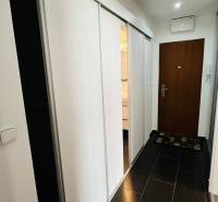 A hallway in a 3-room apartment with sliding doors and a dark brown floor.