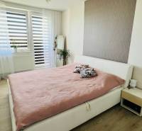 A bright bedroom with a large bed, a mirror, and a wooden decor floor in a 3-room apartment.