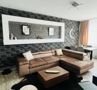 Living room in a three-room apartment with a wooden decor floor and a corner sofa.