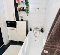 Bathroom with a bathtub, cabinets, and decorations in a 3-room apartment.