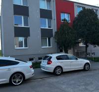 An apartment building in Gbely with a modern facade and parked cars in front of a 3-room apartment.