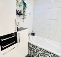 Bathroom in a 3-room apartment with a white bathtub, modern tiles, and storage space.