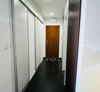 A narrow hallway with a black floor and white built-in wardrobes in a 3-room apartment.