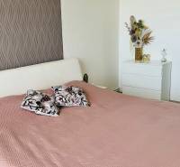 A bedroom in a 3-room apartment with a bed, decorative pillows, and ornamental wallpaper.