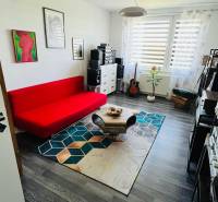 A room with a red sofa and a wooden decor floor in a 3-room apartment.