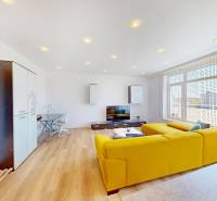 Living room in a two-room apartment with a wooden decor floor and a yellow sofa.