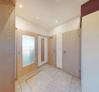 The entrance hall of a 2-room apartment with tiles, light doors, and a mirror.