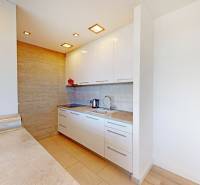 A kitchen in a 2-room apartment with white cabinets and a wooden decor floor.