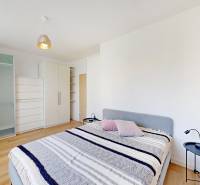 Bedroom in a 2-room apartment with a bed, wardrobes, and a floor with a wooden decor.