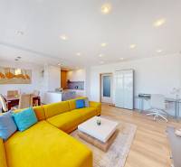 A bright living space with a striking yellow sofa, dining area, and wood-patterned flooring.