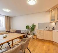 Interior of a vacation apartment with a sofa, kitchen, and wooden decor flooring.