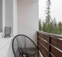 Balcony of a recreational apartment in Poprad with a black chair and a view of the trees.