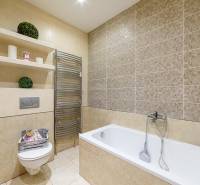 Bathroom with a shower, bathtub, and shelves in a 2-room apartment with neutral tiles.