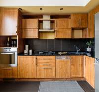 A kitchen in a 2-room apartment with wooden cabinets and a black countertop.