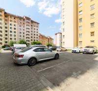 Parking lot on Armádna Street in Trenčín with parked cars in front of apartment buildings.