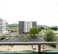 The view from the balcony on Armádna Street in Trenčín, surrounded by greenery and buildings.