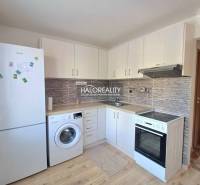 A kitchen in a studio apartment with white cabinets and a wood-patterned floor.