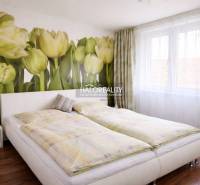 Bedroom in a 4-room apartment with tulip wallpaper and a floor bed with a wooden decor.