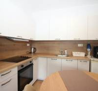 A kitchen with built-in appliances and wooden decor in a studio apartment.