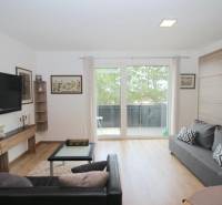 Living room in a one-bedroom apartment with a TV, sofas, and a wooden decor floor.
