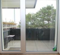 A balcony with sliding doors and a view of trees in a studio apartment on Broskyňová Street in Rovinka.