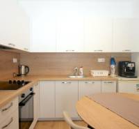 White kitchen with wood decor in a studio apartment with appliances.