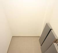 A small storage space in a studio apartment with tiled floors and white walls.