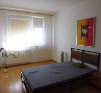 A stylish bedroom in a two-room apartment with a wooden decor floor and an artistic painting.